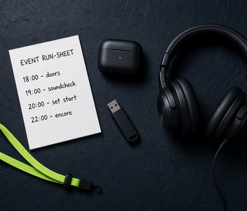 Flat lay of professional DJ booking essentials including headphones, run-sheet and lime-green lanyard